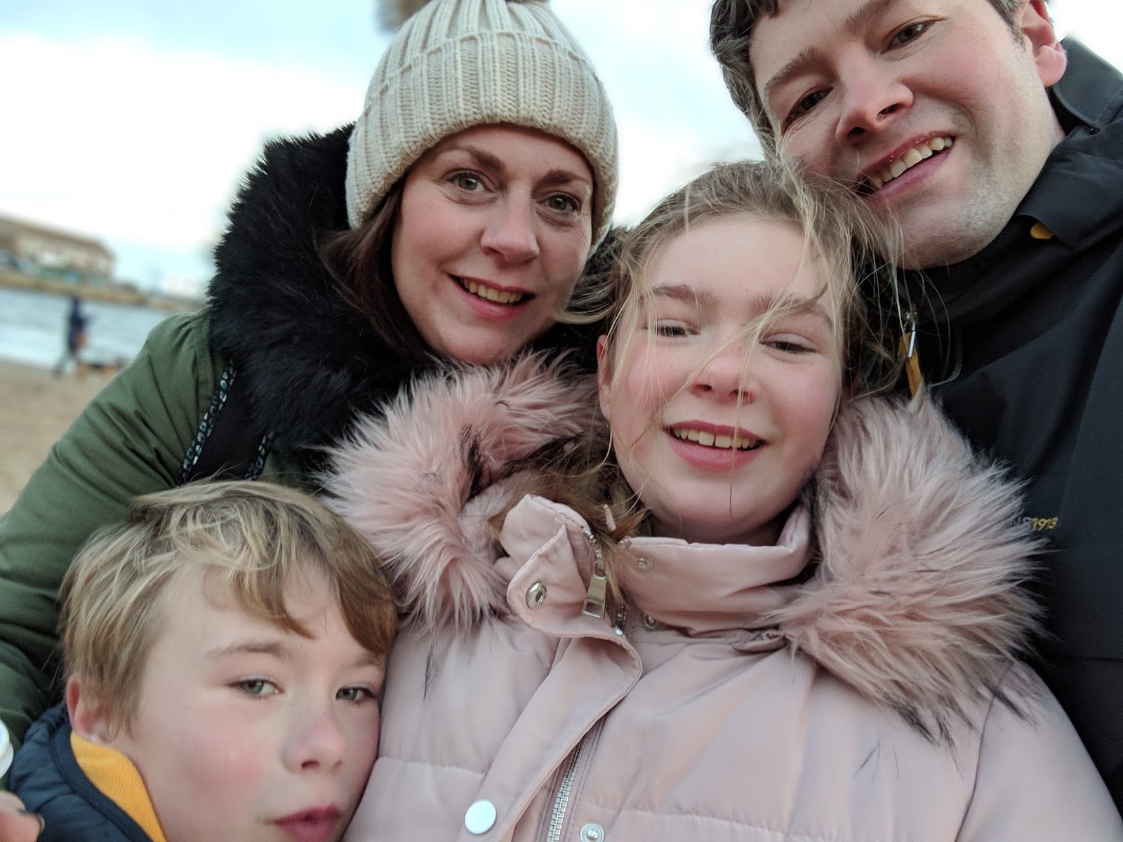Andrew, Emma, Abby and Oliver smiling together by the sea